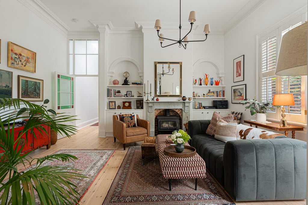 Restored North Adelaide heritage living room with custom fireplace, decorative archways, vintage furniture and curated styling.